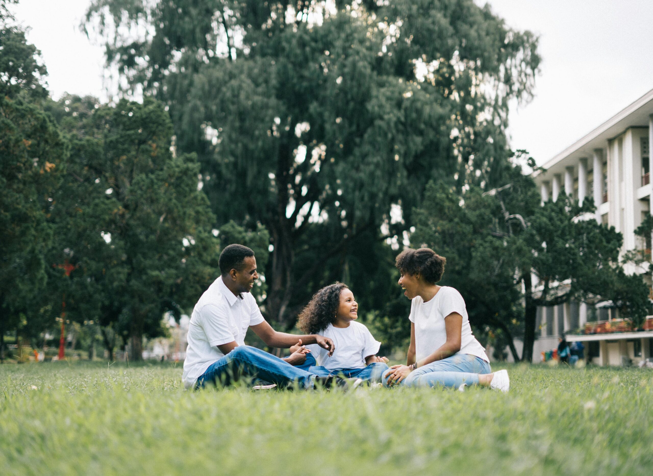 A happy black family enjoying quality time together outdoors in a lush green park.